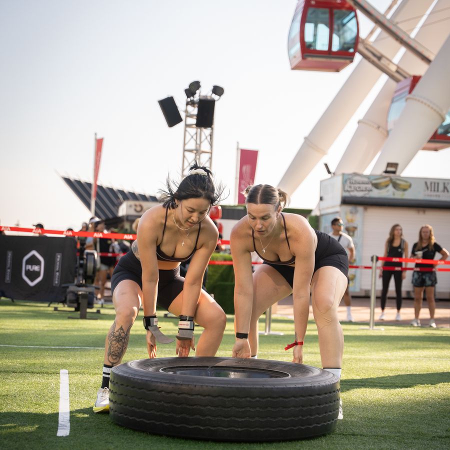 A pair flipping a tyre with the judge alongside