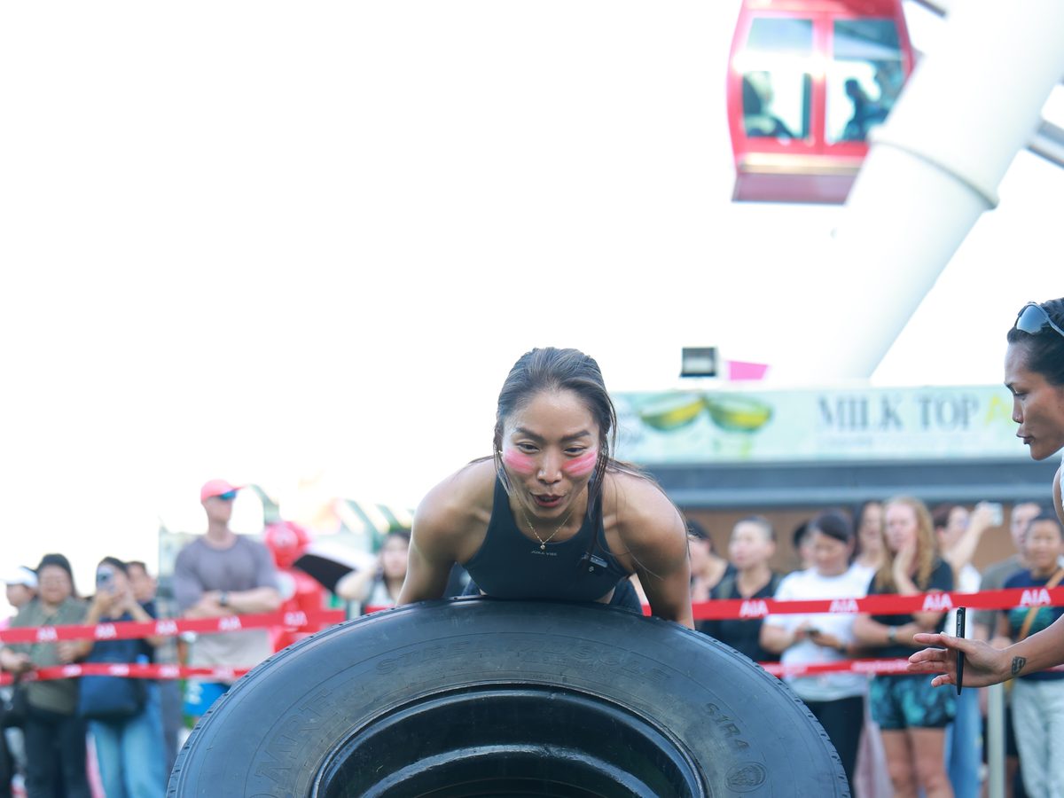 An athlete mid tyre flip below the Hong Kong Observation Wheel